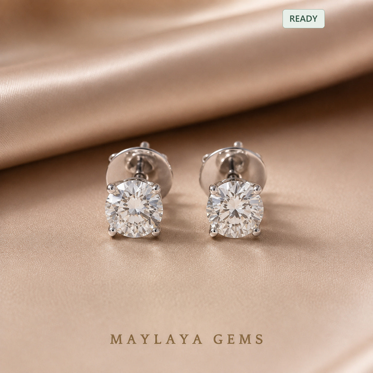 Er002 round diamond stud earrings with four prong white tone gold settings — front view on champagne satin